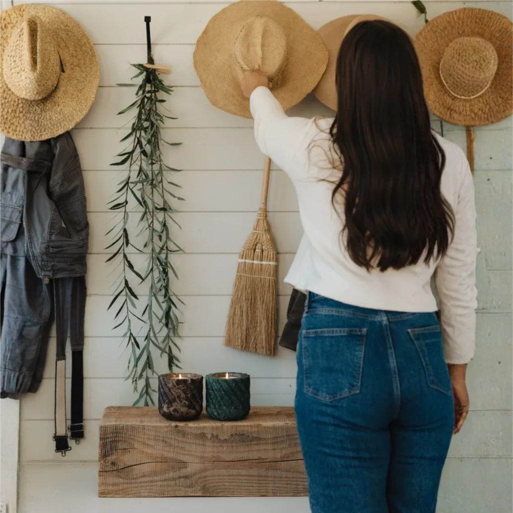 Woman arranging hats on a wall display with rustic decor.